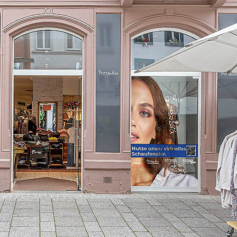 Schaufensterbeschriftung eines Modeladens und Klamotten auf einem Ständer die im Vordergrund stehen.