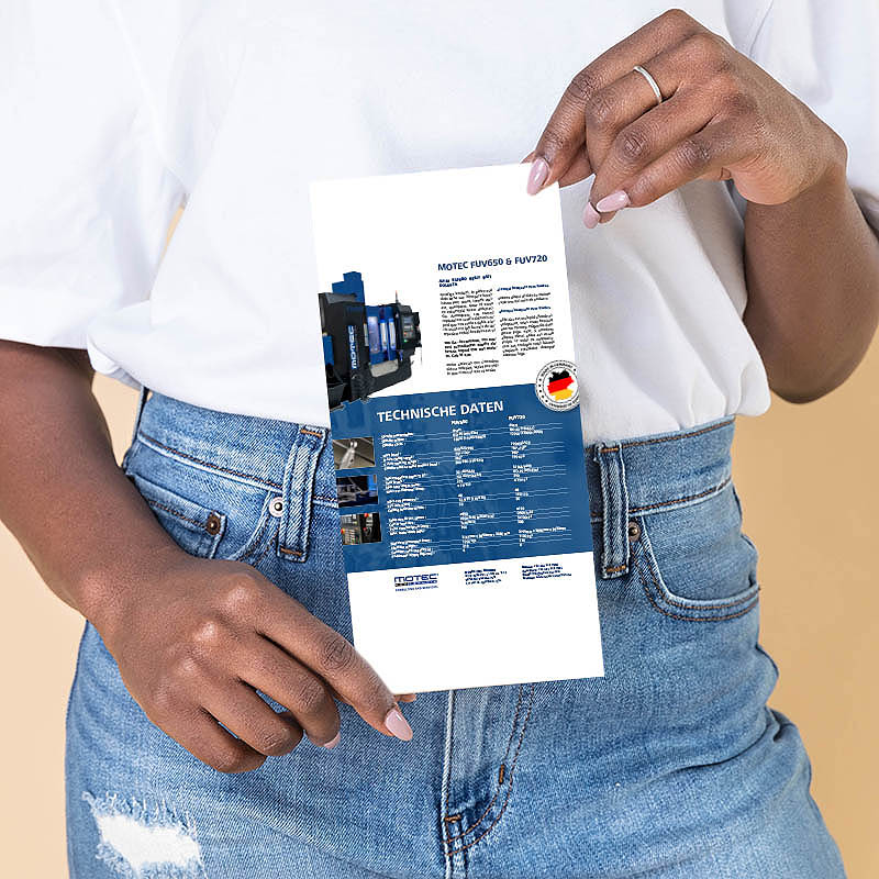 Frauenhände die einen Flyer der Firma Motec halten.