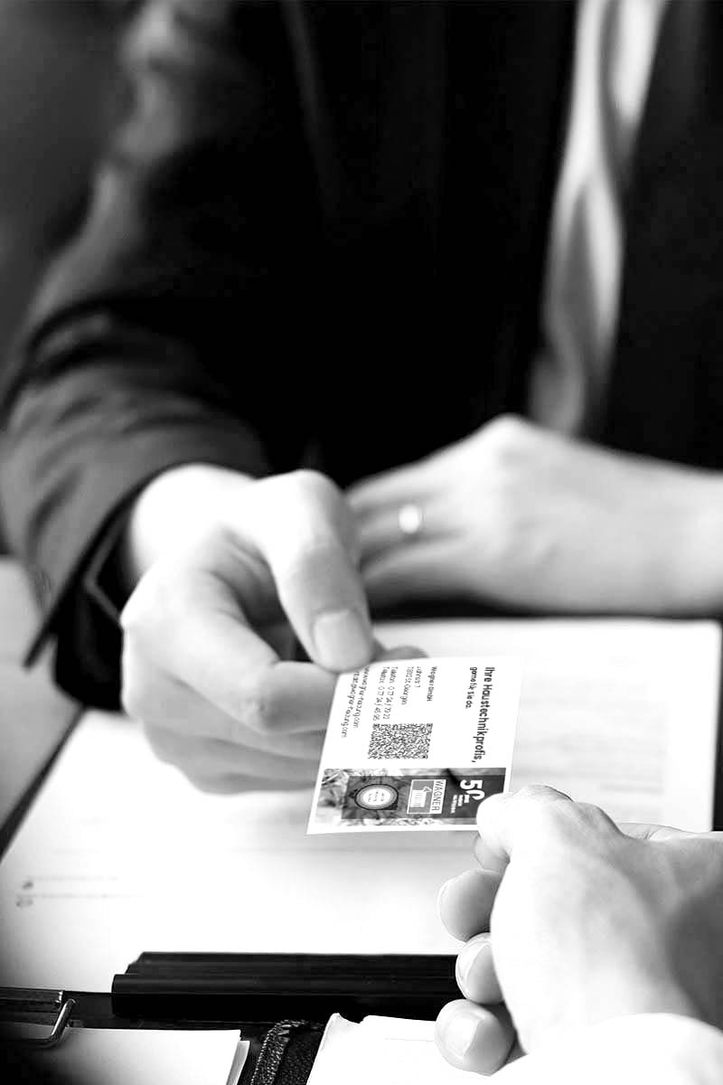 Mann übergibt eine Visitenkarte der Firma Wagner an eine andere Person.