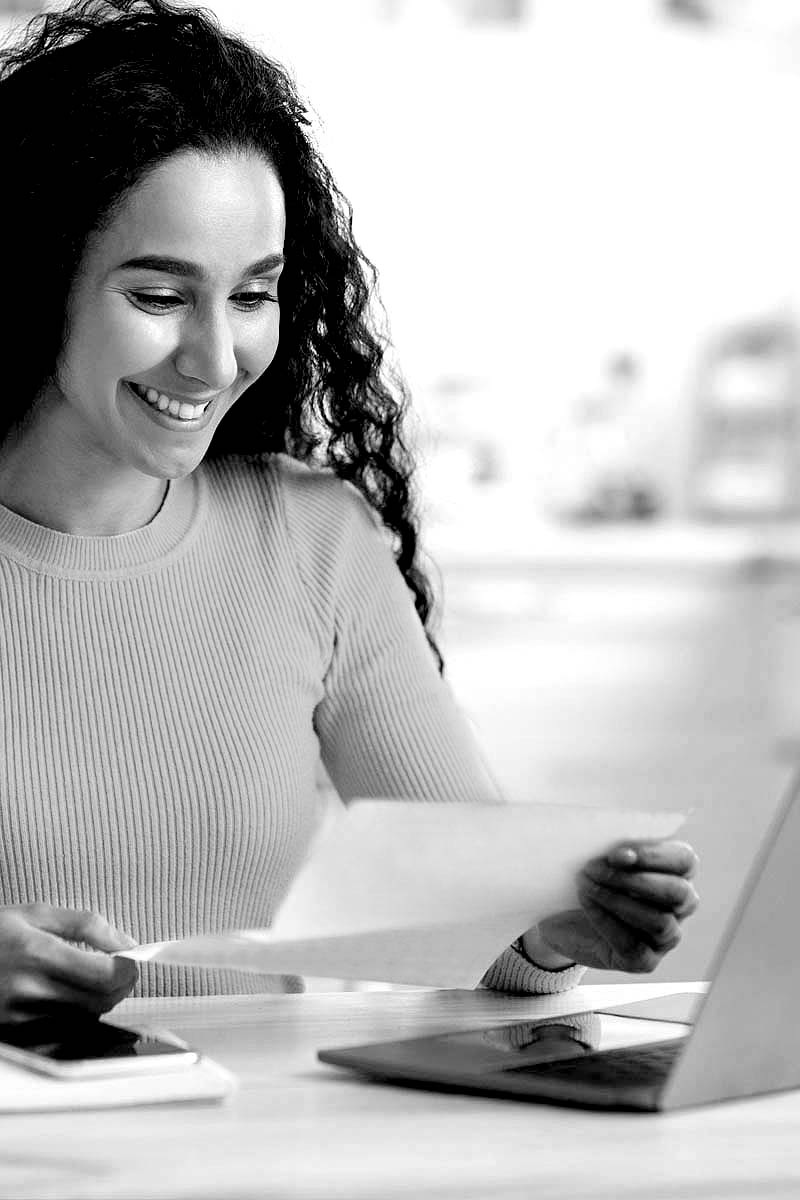 Frau mit Locken liest einen Breif und lächelt.