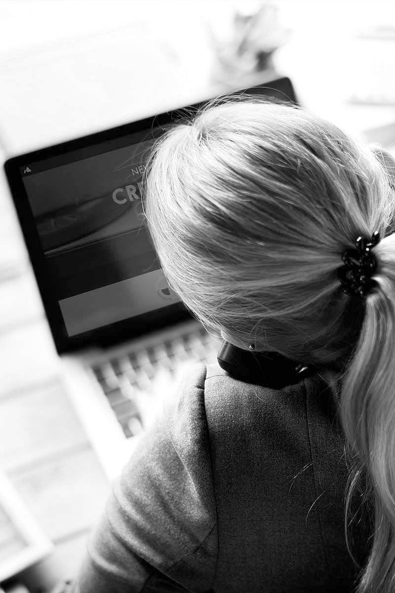 Frau, die am Schreibtisch sitzt, von hinten.