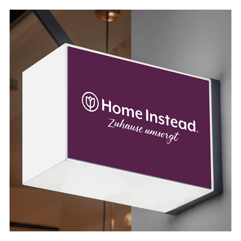 Leutschild von Home Instead an einer Hauswand.